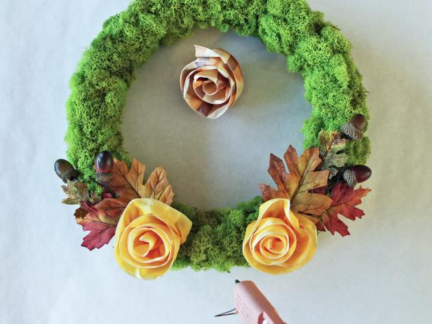 Craft a cheery touch of fall for your front door with a moss-covered wreath form and autumnal ribbon roses. 