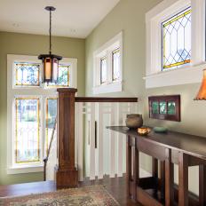 Sea Green Upstairs Staircase Hallway With Stained Glass Window Trim and Yellow Shaded Table Lamp On Wood Table
