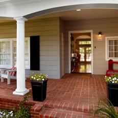 Covered Front Porch With Brick Floor, Neutral Siding, White Support Column and Black Window Shutters 