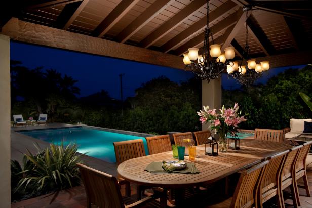 A large outdoor dining table accommodates ten, with two wrought iron chandeliers illuminating the space. The partially covered area allows for outdoor entertaining even when the weather gets bad. Guests have the luxury to take a dip in the pool before or after dinner.
