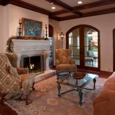 Formal Sitting Room With Wood Frame Arched French Doors, Patterned Traditional Armchairs and Decorative White Mantel 