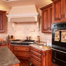Decorative Range Hood Cover Over Stainless Steel Stovetop in Traditional Kitchen With Wood Cabinetry and Granite Countertop 