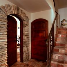 Stone Tile Floor Hallway With Arched Wood Doors, Stacked Stone Door Frame and Stone Staircase 