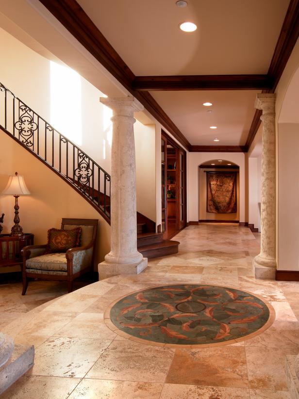 Gorgeous Neutral Foyer With Circular Floor Decor, Distressed Stone Support  Columns and Open Hallway Design | HGTV