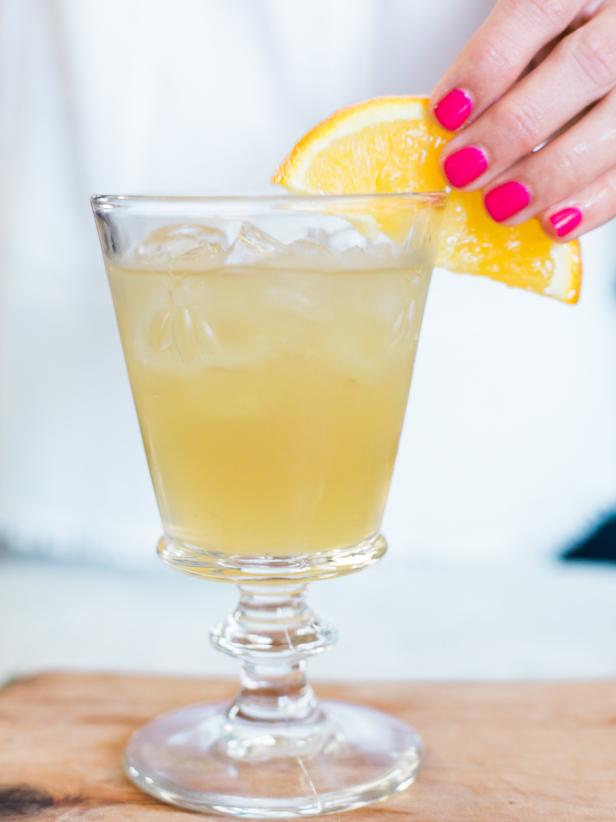 Cut a half-inch notch in each orange slice, so it sits easily on the rim of the glass, then add sage, a straw and serve!