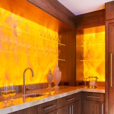 Honey Onyx Wet Bar with Back Lighting and Floating Star Fire Glass Shelving is Focal Point in Living Area