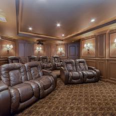Single and Double Brown Leather Seats in Home Theater With Patterned Carpet and Lampshade Sconces 