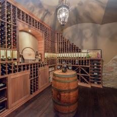 Built In Wood Wine Bottle Storage Shelves in Wine Cellar With Decorative Light Fixture and Natural Rock Wall Detail 
