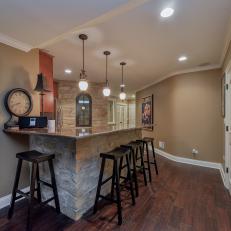 Natural Rock Basement Bar With Black Contemporary Bar Stools, Traditional Pendant Lights and Polished Stone Countertop