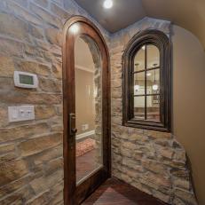 Natural Rock Wall Detailing Around Arched Wood Door and Window in Basement Room 