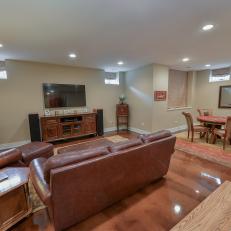 Basement Living Space With Brown Leather Sofa, Mounted Flatscreen TV and Connected Dining Room 