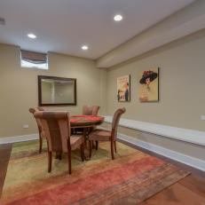 Colorful Striped Rug Under Circular Wood Dining Table and Upholstered Chairs in Basement Dining Room 