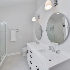 Double Vanity With Mounted Mirrors and Sconces in Contemporary Bathroom Featuring Glass Door Subway Tile Shower 