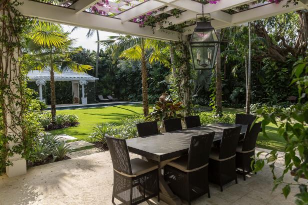 Agregue una lámpara sobre un comedor al aire libre, ya sea que esté completamente cubierto o debajo de una pérgola. Nievera Williams Design diseñó la pérgola, que está cubierta con buganvillas de poca agua, en este patio de Palm Beach, Florida, que ganó un premio de la Sociedad Estadounidense de Arquitectos Paisajistas de Florida.