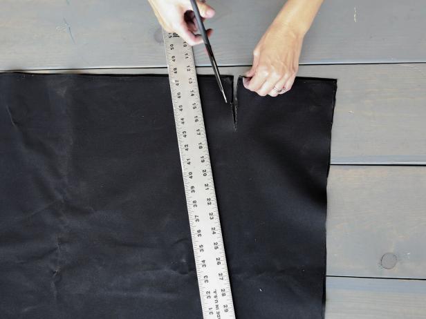 To start, fold your canvas in half and lay it flat. Measure and mark in 7 inches from the open top corner.  Using a yardstick, draw a line from the mark to the bottom corner. Cut off the angled corner piece and discard.