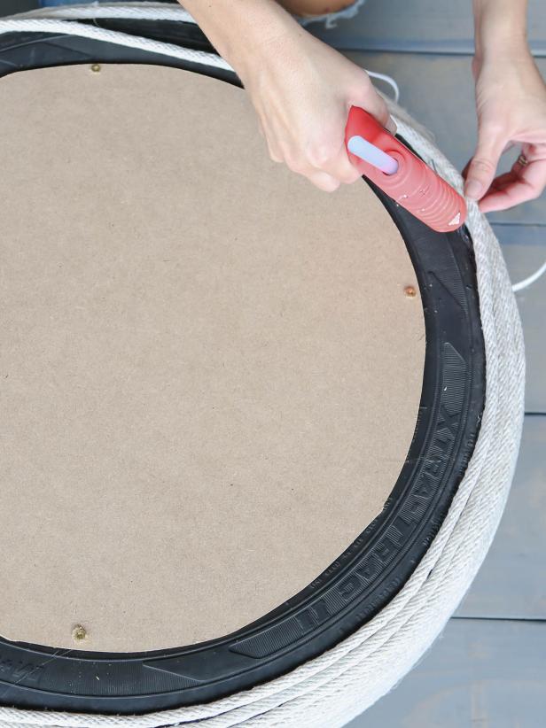 Starting on the top center of the circle, glue the clothesline in a tight spiral. Use a good amount of glue and try to not leave any gaps between the rope. Keep adding rope until it reaches the edge and continue down the sides of the tire. Flip the tire over and add rope until you cover the bottom side.