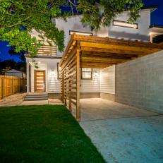 Concrete Patio With Wood Pergola, Cement Brick Wall and Outdoor Lighting Illuminating Walkway to Door 