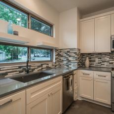 Black and White Thin Tile Backsplash in Modern Kitchen Featuring Stainless Steel Appliances and Gray Countertops 