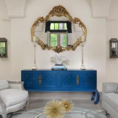 Bold Blue Dresser and Gold Mirror Create Vibrant Vignette in Black and White Living Room