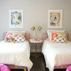 Pink and Gold Girl's Bedroom With Colorful Pillows and Paintings