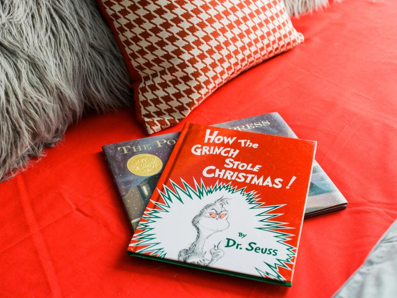 Christmas theme books on red blanket with throw pillows