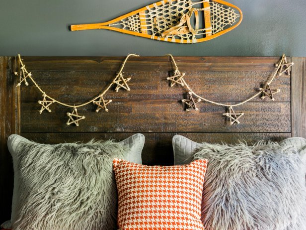 headboard with twig, star garland, a snowshoe hanging about it and throw pillows