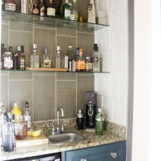 Small Industrial Bar Area with Glass Shelves and Granite Countertop