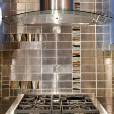 Modern Kitchen with Silver and Glass Hood Vent and Silver, Brown and Green Colored Tiles
