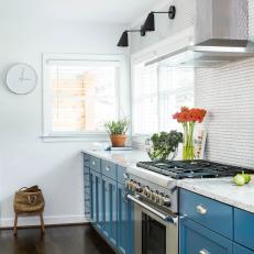 Modern White and Blue Kitchen with Metal Vent Hood, Tile Backsplash and Simple Sconces and Clock
