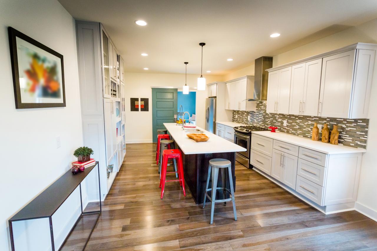 Bright Open Plan Kitchen With White Cabinets And Red Metal Stools