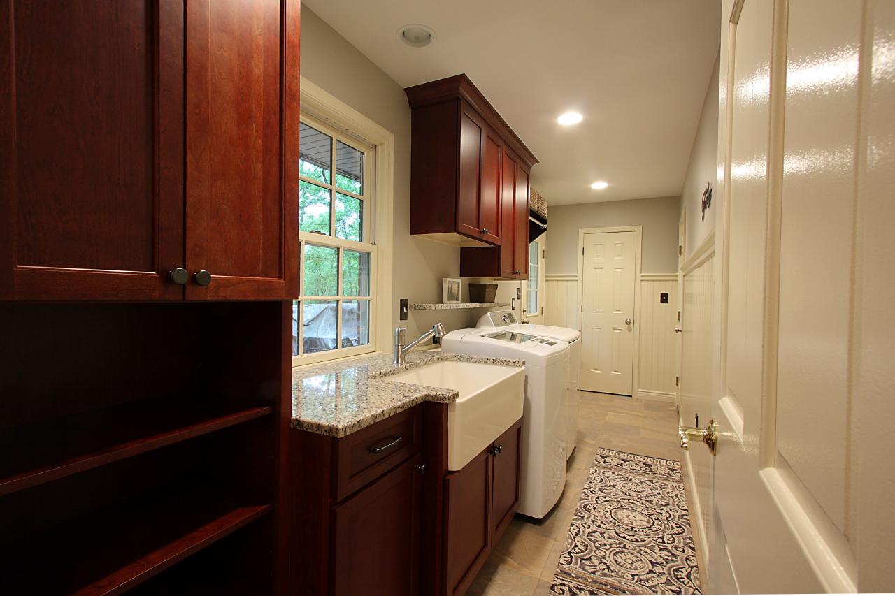 Spacious Laundry Room With Cherry Wood Cabinets And Farmhouse Sink