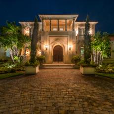 Enticing Home Exterior With Brick Driveway and Walkway, Arched Wood Front Doors and Garden Framed Entrance 