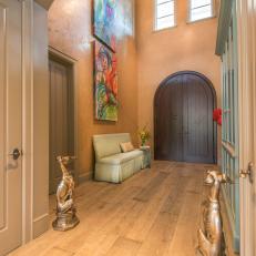 Grand Entrance With High Ceilings, Colorful Abstract Art, Arched Wood Doors and Dog Statues 