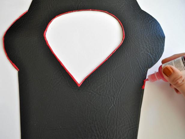 Fold synthetic leather in half and place pattern on leather with shoulders placed on the fold. Trace pattern onto leather. Cut out leather outline. Cut out head opening with a “V” in the front and rounded in the back making a raindrop-shape when armor is opened. Try on child and enlarge hole until the fit is correct. Outline edges of armor with 3-D fabric paint. Add additional lines to create visual interest. Cut two parallel diagonal slits across the back of the armor so that the sword can be slipped through.