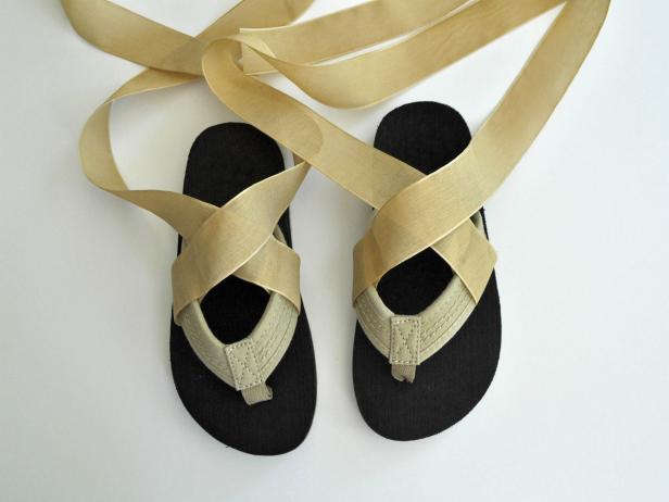 Cut spool of ribbon into four equal parts. Wrap ribbon around flip flop strap, and glue as shown. Repeat on other side of flip flop so there are two straps on each sandal. Repeat on other flip flop. Lace shoes up the leg. Tie in a knot, and tuck in edges of ribbon.