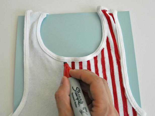 Place paper inside shirt to avoid marker bleeding onto other side. Draw stripes on tank top with permanent marker or fabric marker. Use ribs of shirt as a guide and pull marker along fabric rather than pushing it.