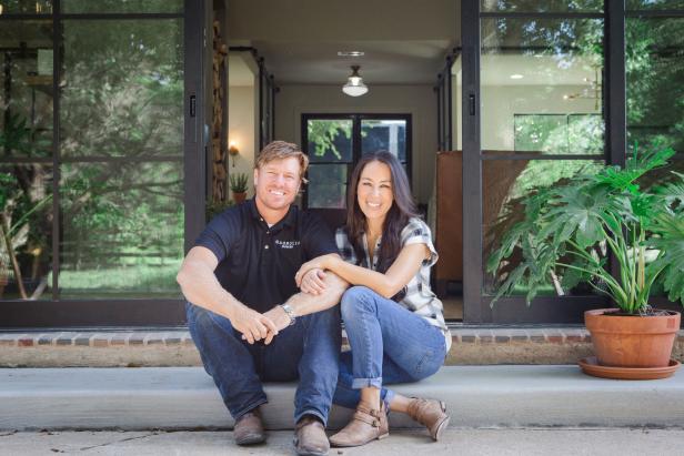 Joanna and Chip Gaines sit outside a newly renovated home.
