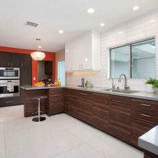 Spacious Midcentury Modern Kitchen With White Subway Tile Backsplash, Woodgrain Cabinetry and Orange Accent Wall