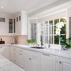Bay Window Shining Over White Countertop and White Cabinetry in Timeless Transitional Kitchen 