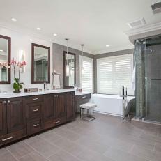 Spacious Master Bathroom With Large Gray Floor Tile, Rich Wood Double Vanity and Glass Shower