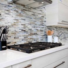 Neutral Marble Tile Backsplash Over Built in Countertop Stovetop and Midcentury Modern White Cabinetry 