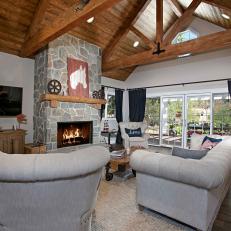 High Ceiling Living Room Featuring a Gray Stone Fireplace Surround, Decorative Exposed Beams and Neutral Furniture