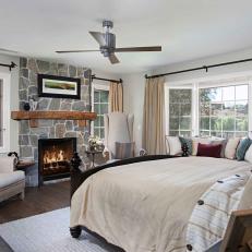 Country Bedroom Featuring Bay Window Seat, Neutral Linens and Natural Stone Fireplace Surround 