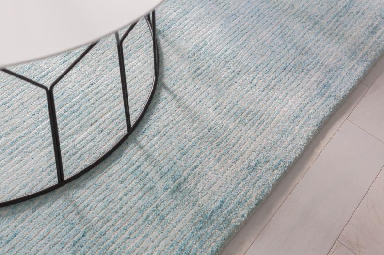 A hand-loomed area rug in a soft aqua adds cushion over the floor and provides a soothing backdrop for this seating area where guests can enjoy a drink and good conversation.