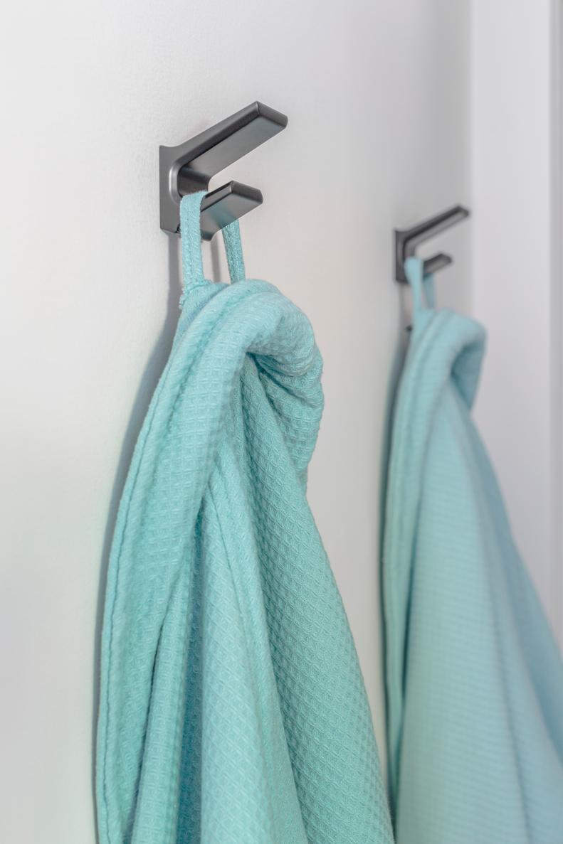 Double robe hooks on the bathroom wall offer easy access to cotton spa bathrobes that provide cozy warmth after a shower. 