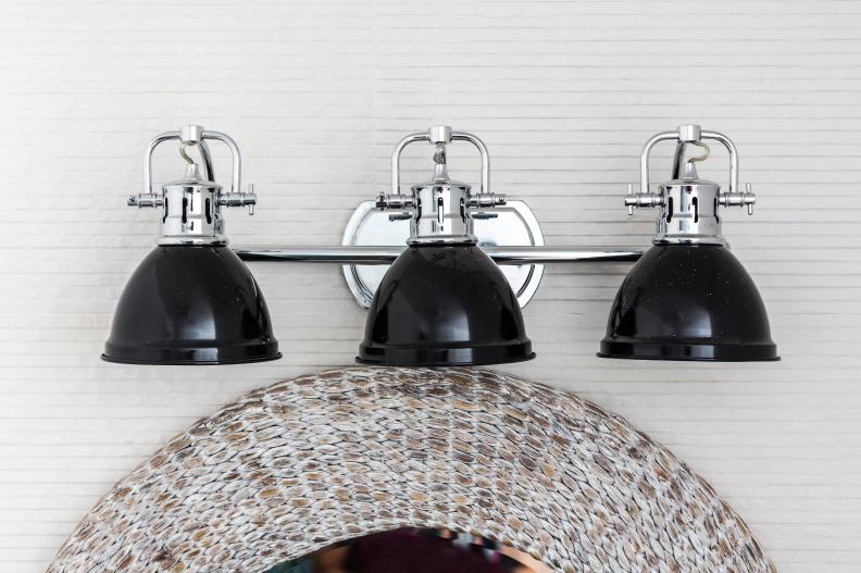 A mix of contemporary style with an industrial feel, a 3-light metal vanity light with glossy bowl shades in chrome and black provides illumination.