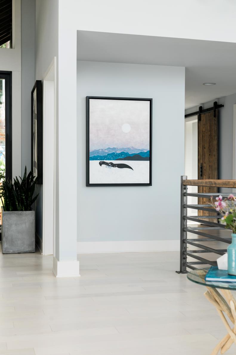Clean white walls and whitewashed floors combine to make the perfect at home gallery.  The soft pinks and blues found in the painting echo the color palette found in the rest of the great room.