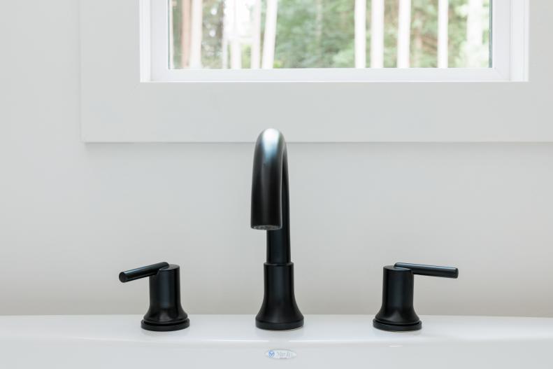 The matte black faucet feels timeless and adds a masculine touch to this sleek, white bathroom.