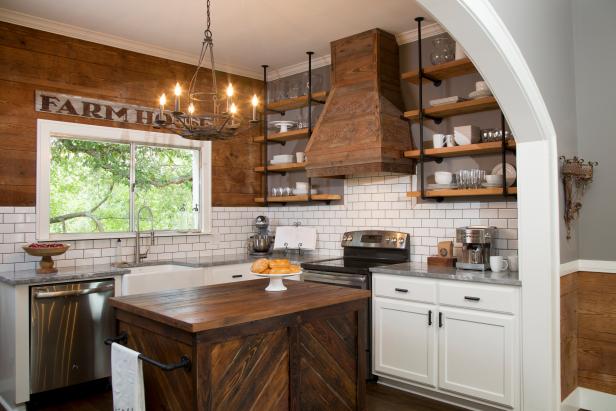 Hosts Chip and Joanna Gaines expanded the entryway to the kitchen by cutting a wide archway, which creates a better flow between the kitchen and dining room.  They painted one wall a neutral gray and for the other, they brought in shiplap to match the rest of the house.  A white subway tile backsplash and Super White Quartzite countertops add a modern element.  There are new cabinets, a wood vent hood, stainless appliances and an under-mounted sink.  Modern shelving made from plumbing pipes and wood planks offer additional open storage, and a custom kitchen island made from vintage wood contributes style and utility in the kitchen, as seen on HGTV's Fixer Upper.   After #5a (afters)