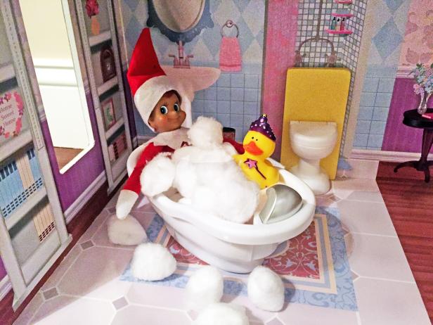 A toy elf in a small toy bathtub in a dollhouse. 